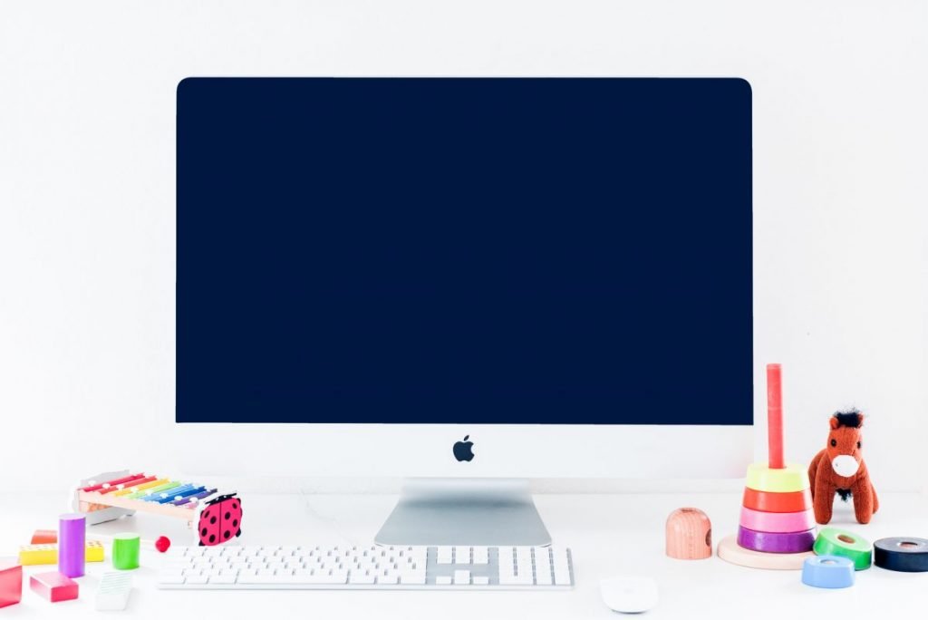 A laptop on a desk beside children's therapy toys, set up for a virtual session